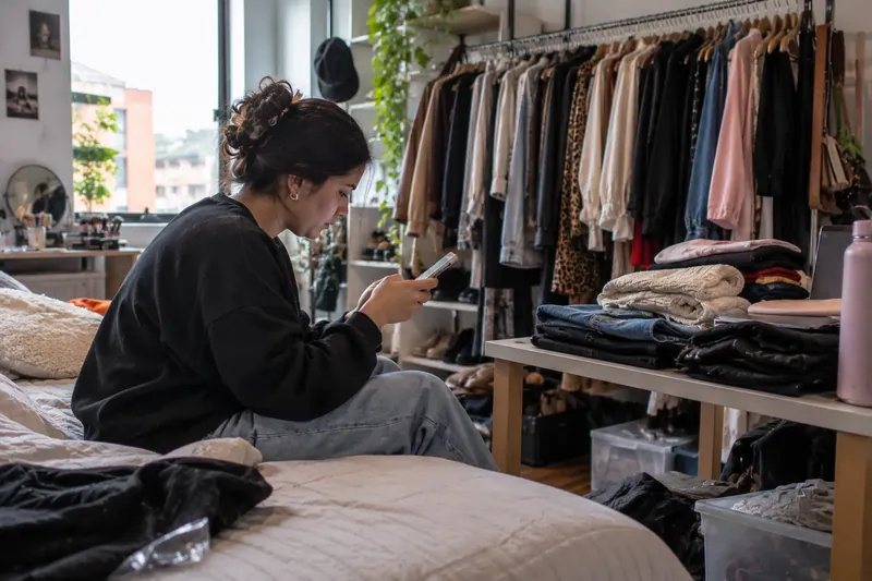 Crear link en bio: joven que vende ropa por Instagram arma su enlace en el celular junto al perchero